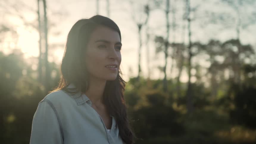 A woman is standing outdoors at dusk