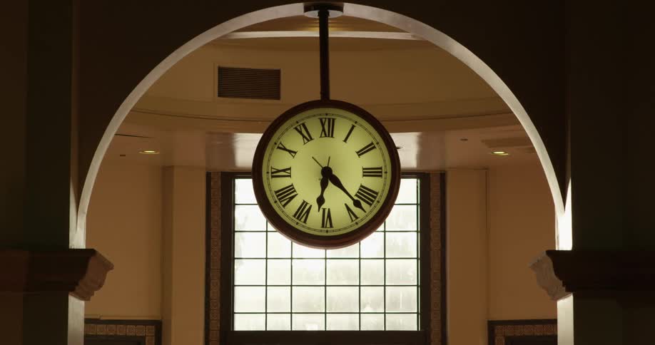 A clock hanging from an archway inside of a building