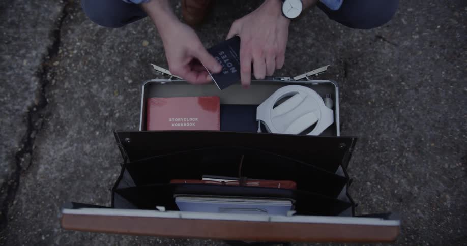 Man opens a suitcase and takes out small booklet