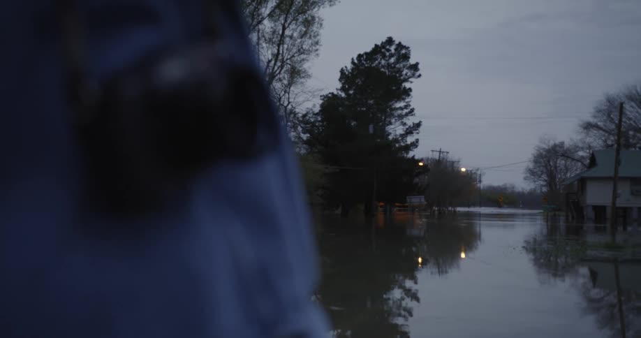 A person with a camera around their neck looks at a flooded street