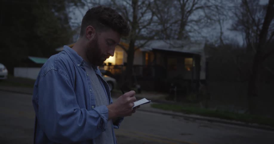 A man writing a note in a neighborhood