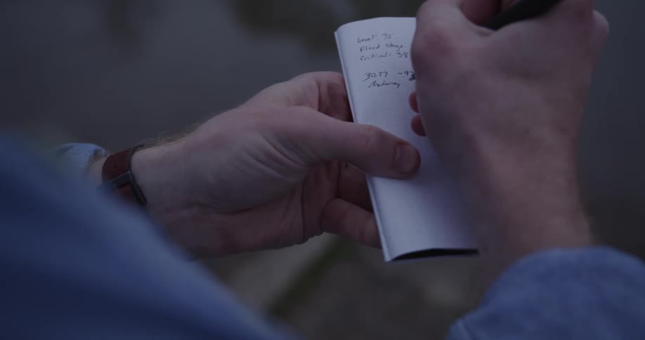 Notes being taken with a pen on a little pad in little light