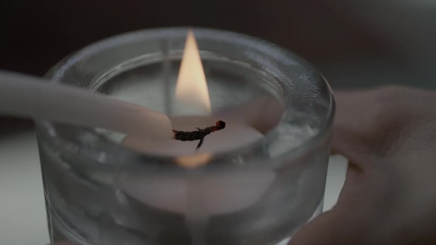 A small candle is lit in a jar