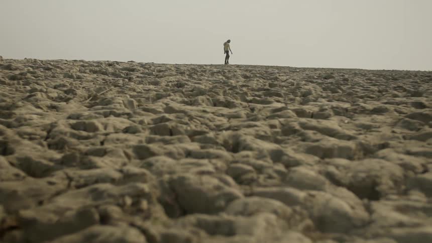 A man walks across the top of a rocky hill