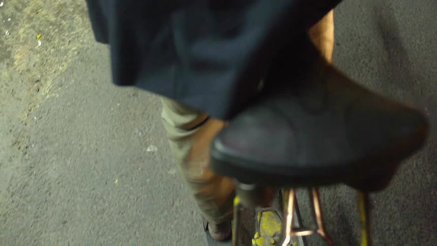 A man walks a few steps before hopping onto his bicycle and riding it