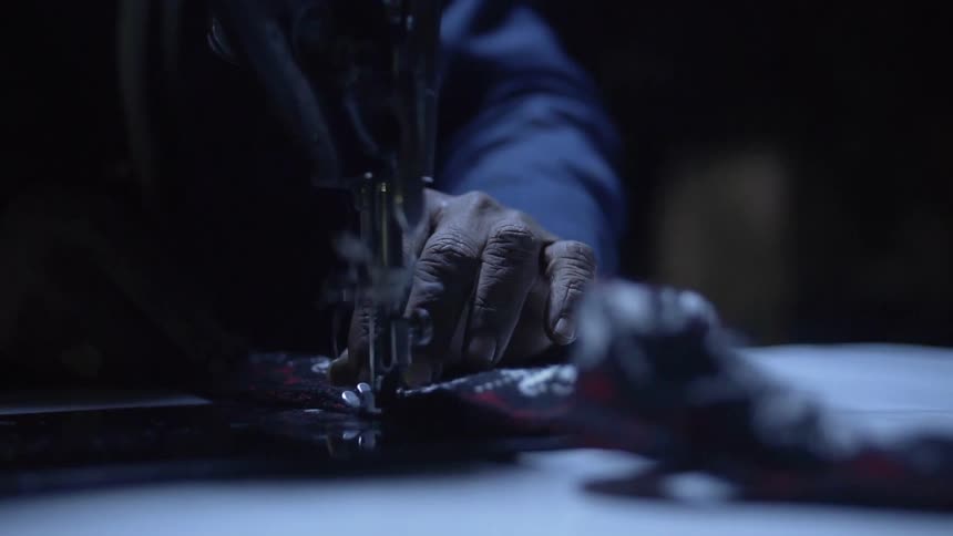 A person sews using a sewing machine