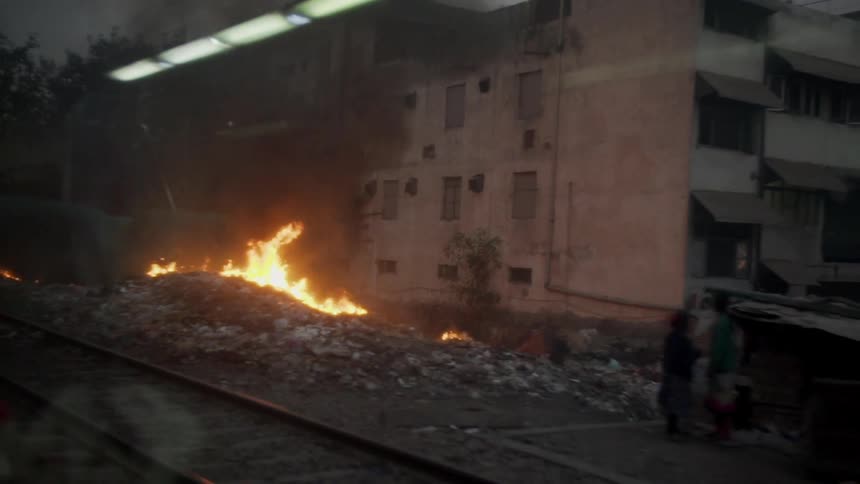 People live in tents along a train track and build fires to keep warm