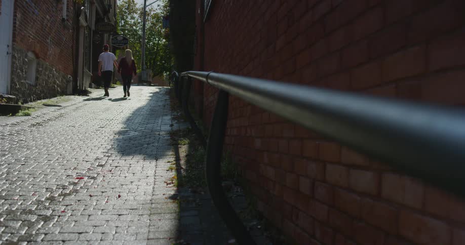 Man and woman holding hands walk up the narrow street