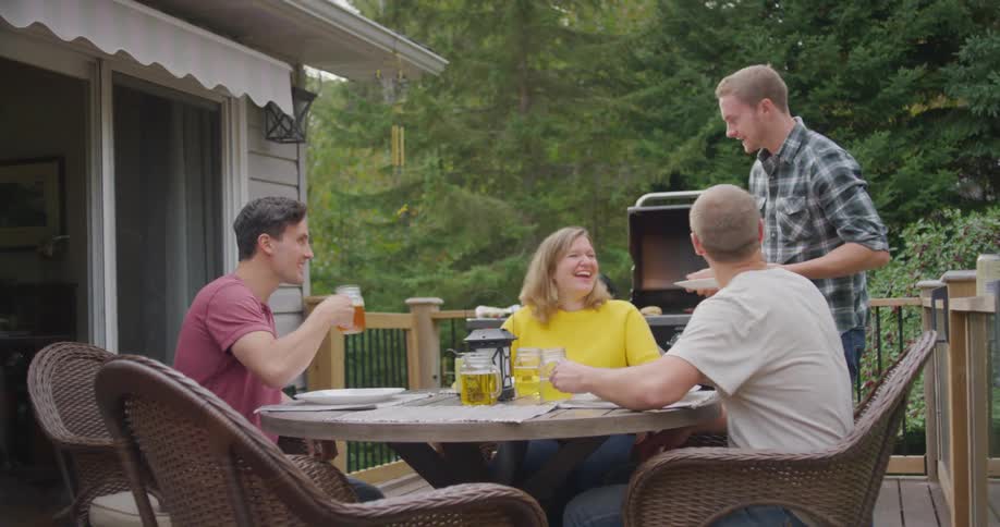 Three gown men siblings gather with their mother at an outdoor patio table with drinks