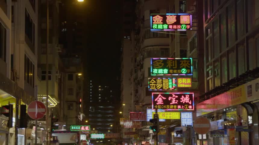 Shopping district at night with neon signs and large buildings