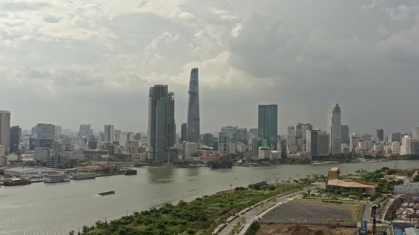 A small boats sails past a marina and city skyline