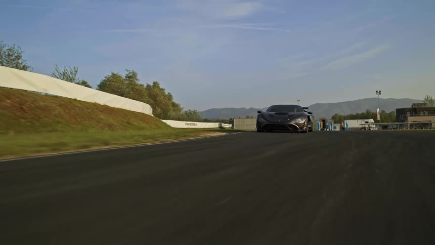 A black sports car is driving on an asphalt race track during the day
