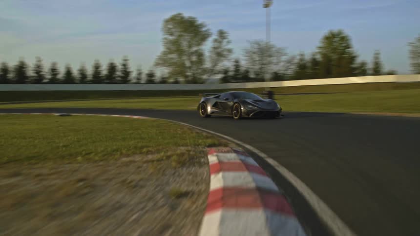 A sports car rounds a corner on a race track during the day