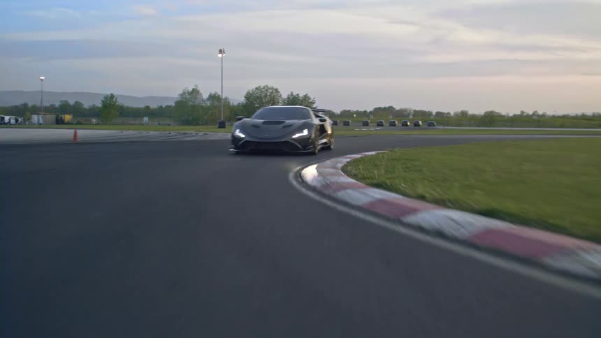Sports car speeding on a winding track at sunset