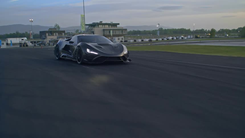 Black luxury vehicle driving on a race track in the evening