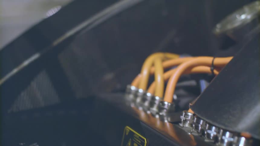 Wires and hose connections of uncovered engine contrast with black of surrounding surfaces