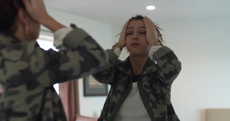 A woman is doing her hair while looking in a mirror