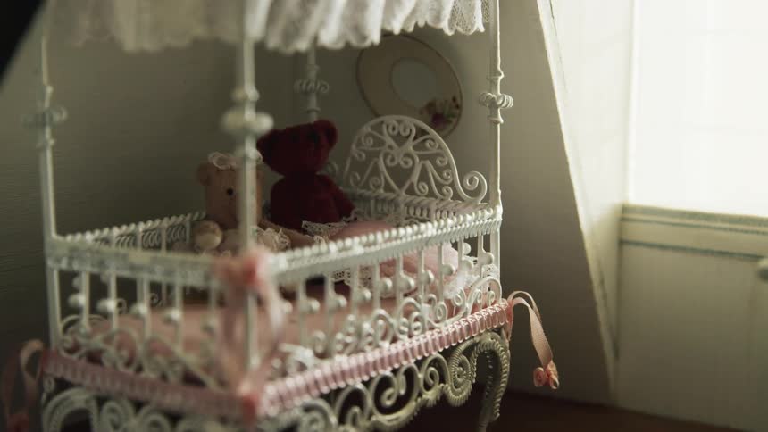Toy crib with small stuffed bears inside of a miniature room