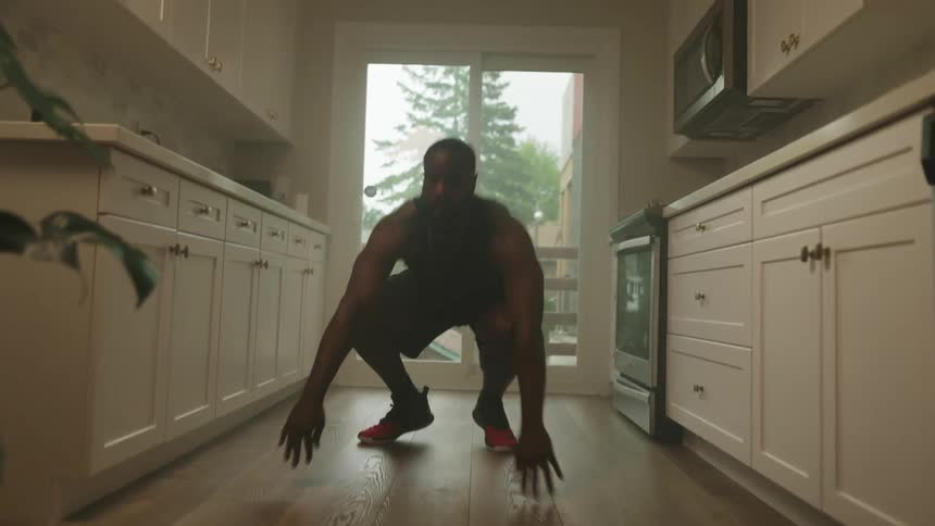 Muscular man with a beard does push ups in the kitchen