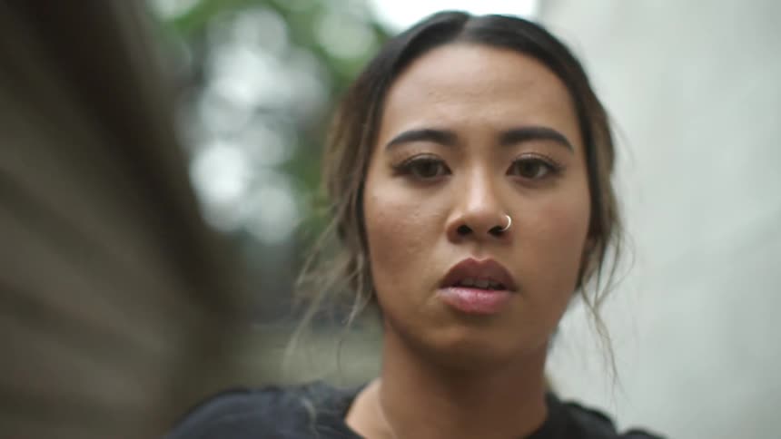 A young woman outside looks around nervously