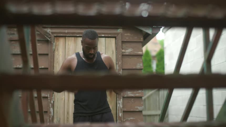 A man stands in front of a set of stairs and moves his arms back and forth