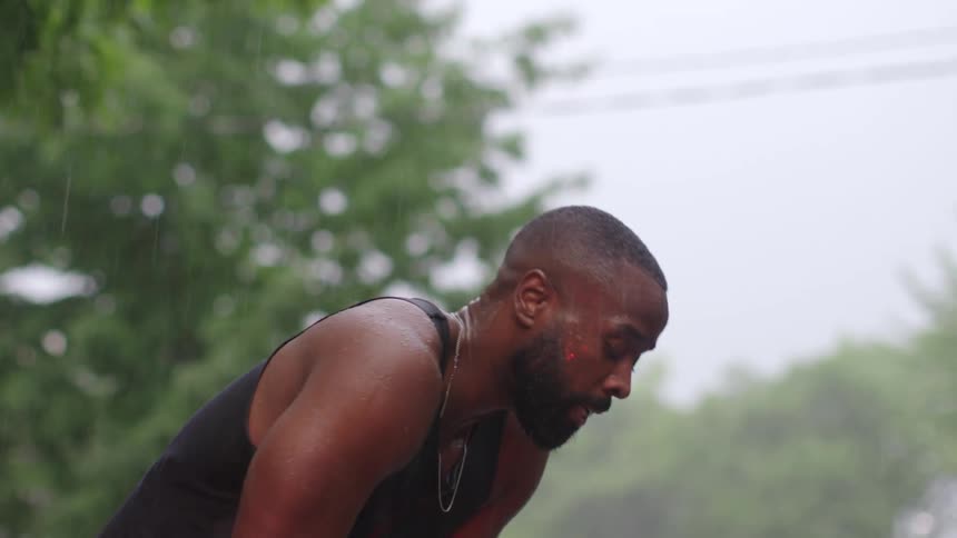 Man standing outside in the rain catching his breath from exercising