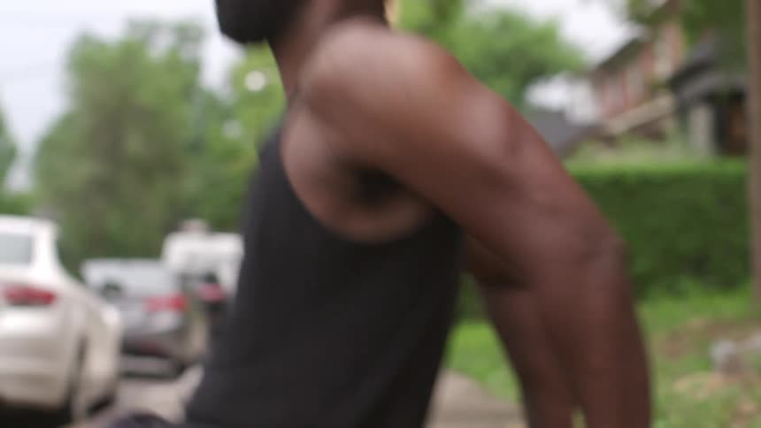 Man exercises on retaining wall bordering sidewalk near house