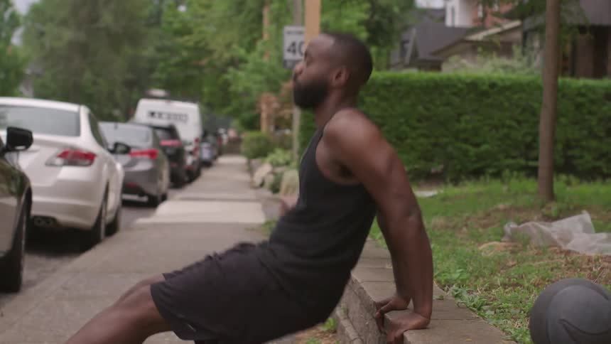 A man works out using a concrete brick retaining wall