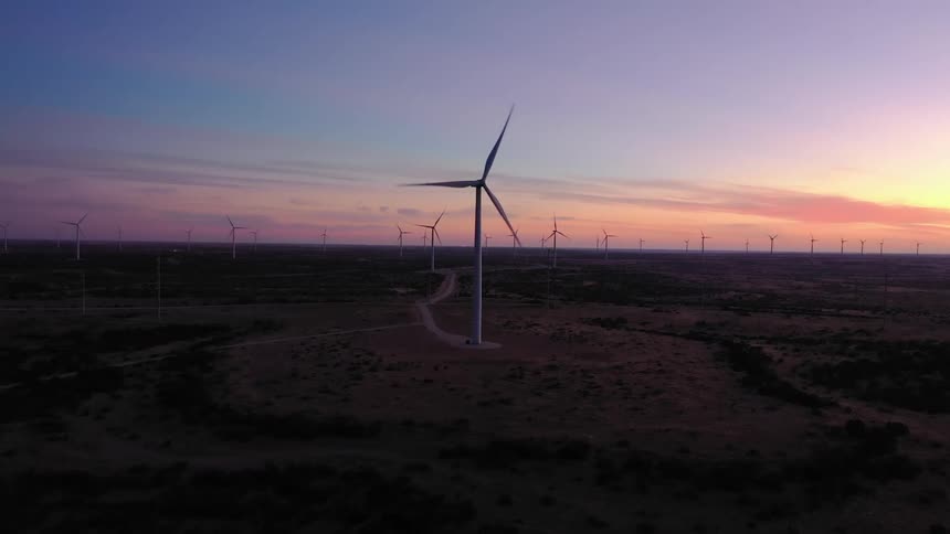 Aerial view of wind turbines rotating in the wind farm at dusk