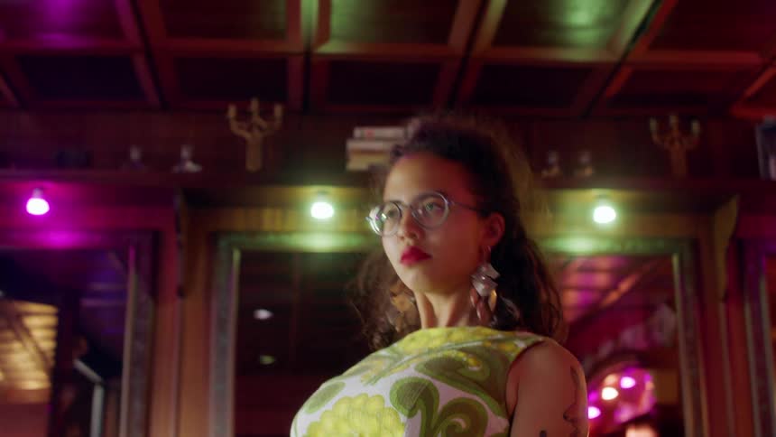 A young woman in an apron dances in an empty bar