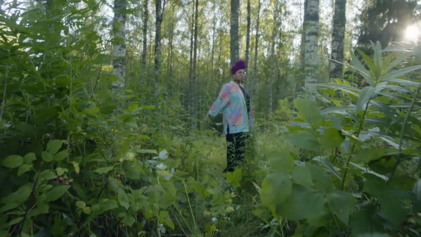 A young woman dancing in a woodland stops to pose