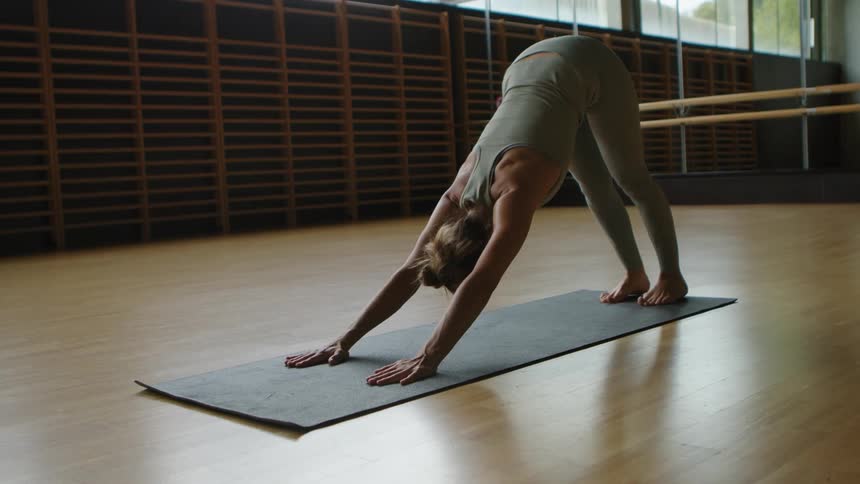Woman with a grey sport top and leggings does push ups on a grey pilates mat in the gym