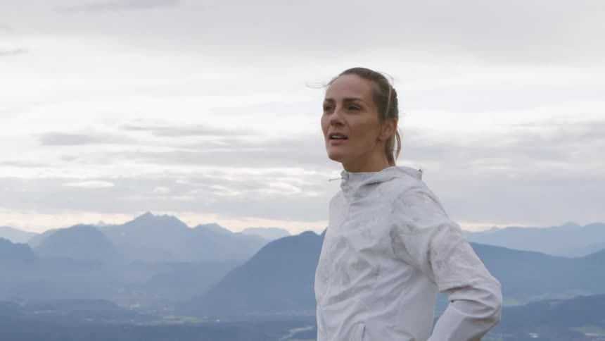 A woman working out outdoors stop to rest at a location with clear views of a mountain range
