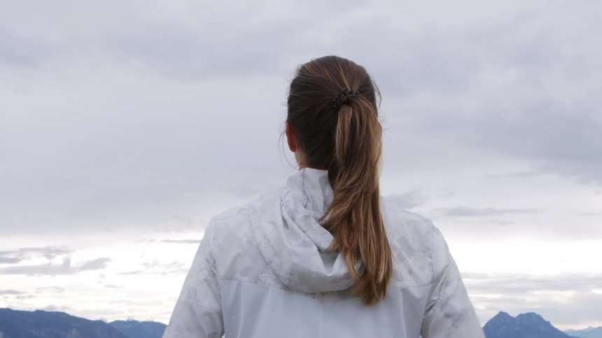 A woman puts her hands to her hips as she turns to look at the mountain view