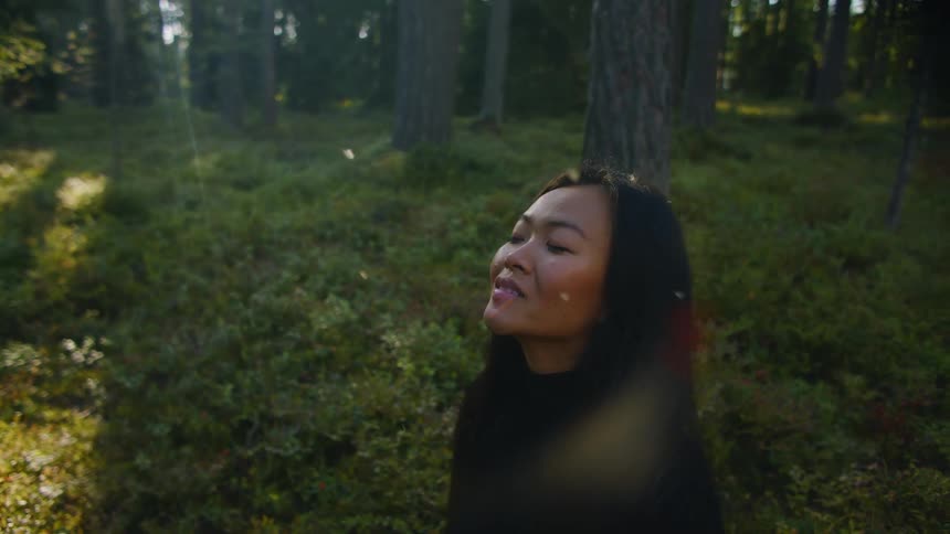 A woman is sitting on the ground in a forest