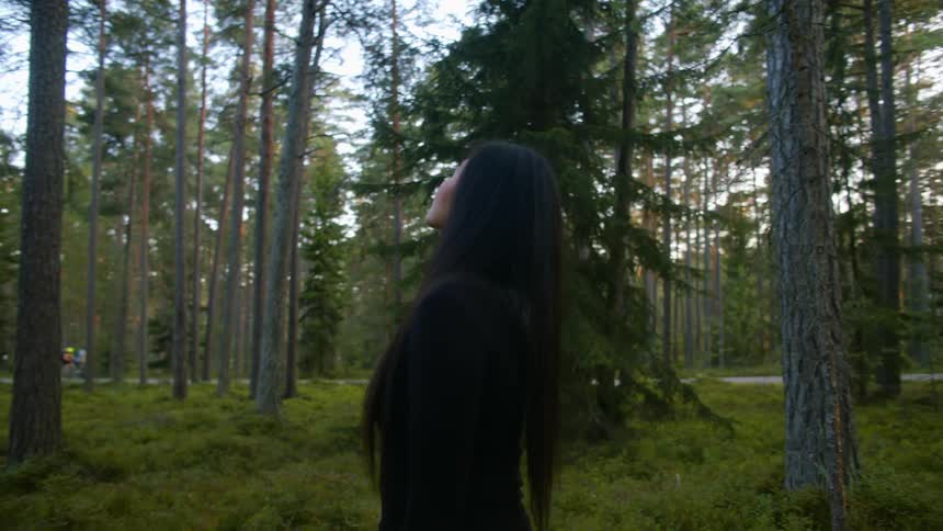 A woman is standing in the woods during the day