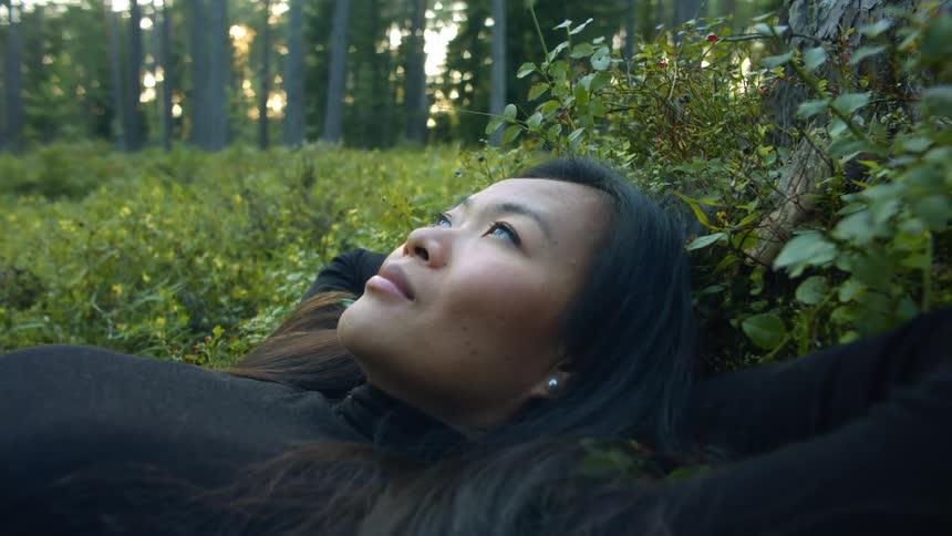 A woman is laying outdoors in the grass