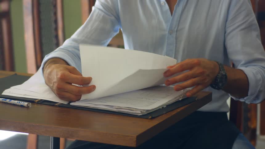 Man sitting at a small desk looking through paperwork