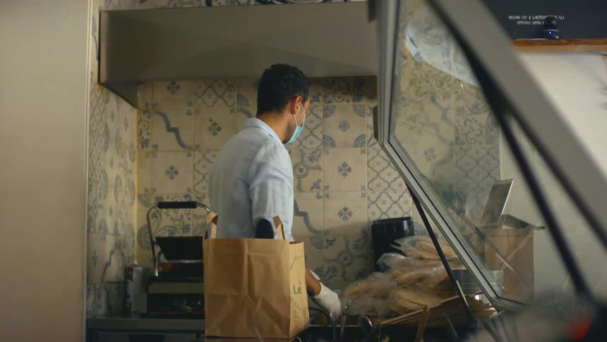 Man standing behind a food counter arranging items working