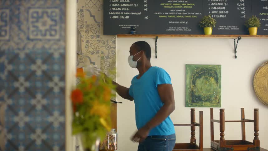 Customer wearing face mask receives takeout order and leaves with a wave