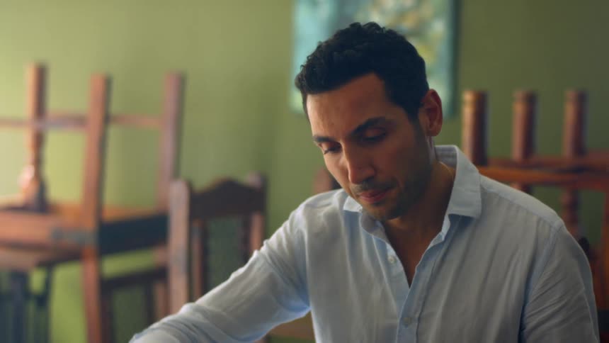 A man sitting at a desk looking at a binder with chairs in the background