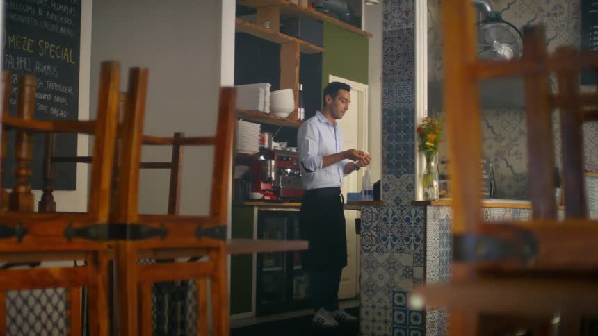 A man standing in the kitchen of a closed restaurant rubs his hands together people putting on plastic gloves