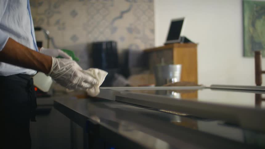 A person sprays a counter and wipes it down