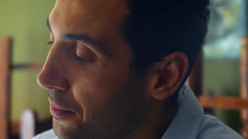 Side view of a stressed man with a stubble beard and a blue shirt