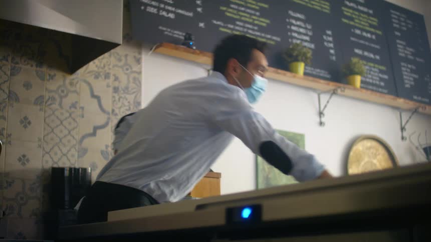 A man wipes down a counter at a restaurant