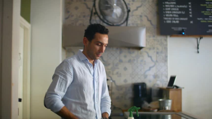 A man ties an apron around his waist and rubs his hands together