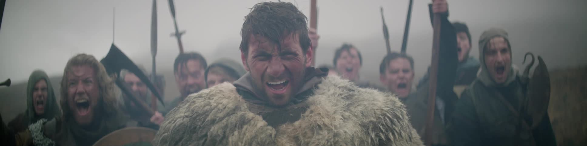 A group of men carrying weapons do a war cry