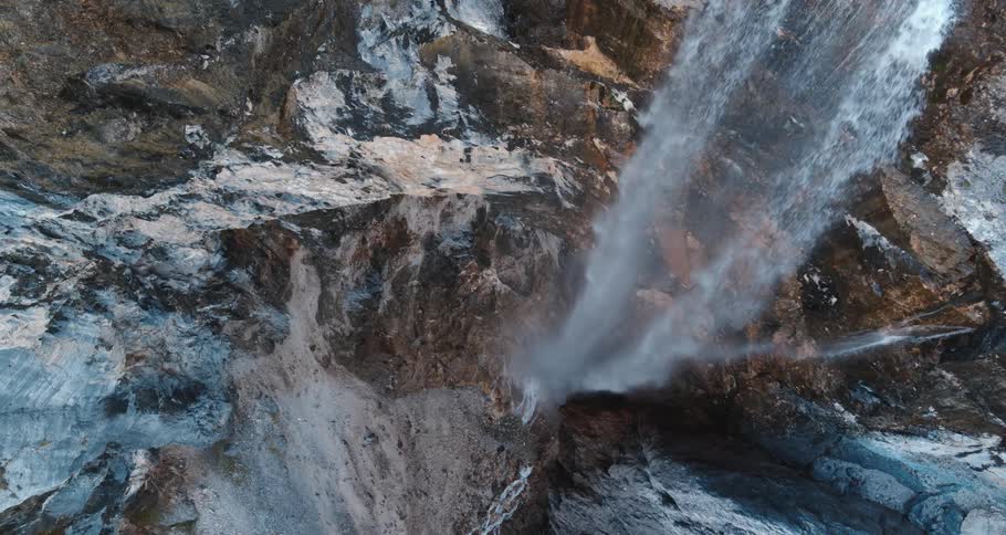 Water falls down a cliff in a canyon filled with trees