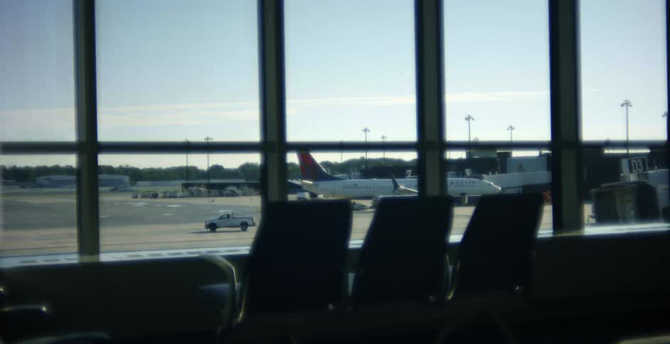 Inside of an airport with a view of a parked plane on a runway outside