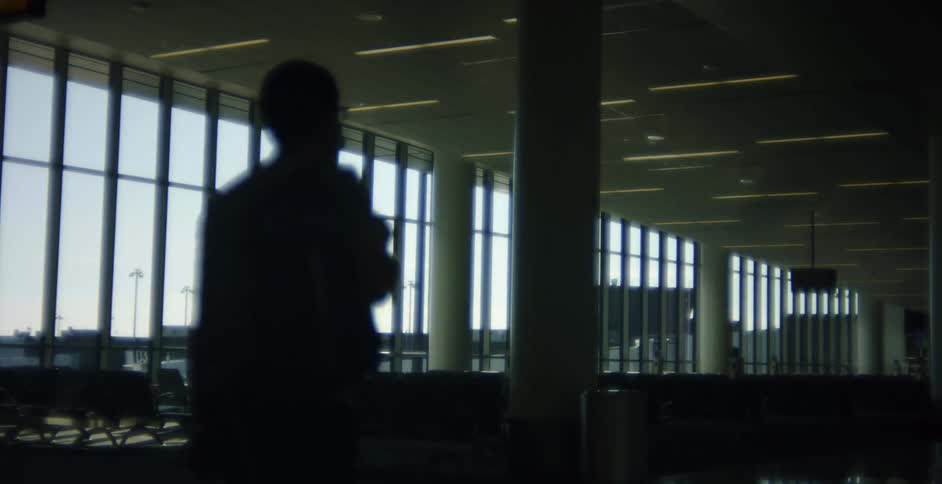 Man and woman walking in the airport terminal are silhouetted against the sky